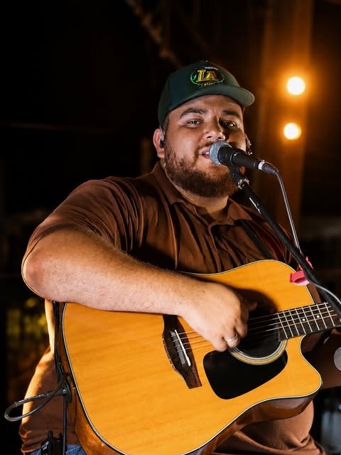 Cantor tocando violão no palco do Terraço do Lago